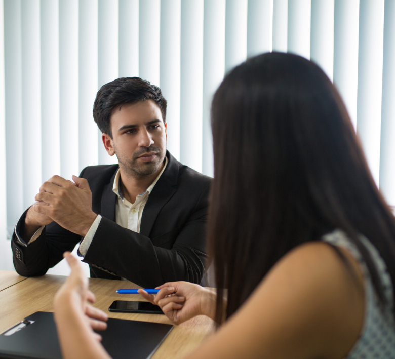 Serious executive listening to female partner or employee. Young Caucasian CEO having meeting with young businesswoman in boardroom. Meeting concept